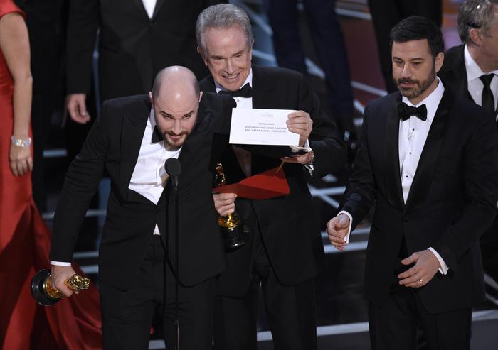 Jordan Horowitz, producer of "La La Land," shows the envelope revealing "Moonlight" as the true winner of best picture at the Oscars on Sunday, Feb. 26, 2017, at the Dolby Theatre in Los Angeles. Presenter Warren Beatty and host Jimmy Kimmel look on from right. (Photo by Chris Pizzello/Invision/ANSA/AP) [CopyrightNotice: 2017 Invision]