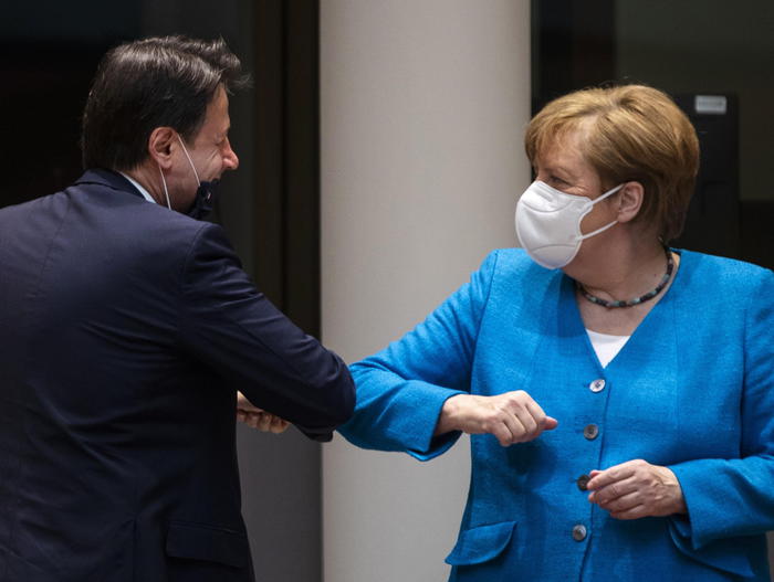 epa08553120 Italy's Prime Minister Giuseppe Conte (L) and German Chancellor Angela Merkel (R) greet each other with an elbow bump at the start of the second day of an EU summit in Brussels, Belgium, 18 July 2020. European Union nations leaders meet face-to-face for the first time since February to discuss plans responding to coronavirus crisis and new long-term EU budget at the special European Council on 17 and 18 July.